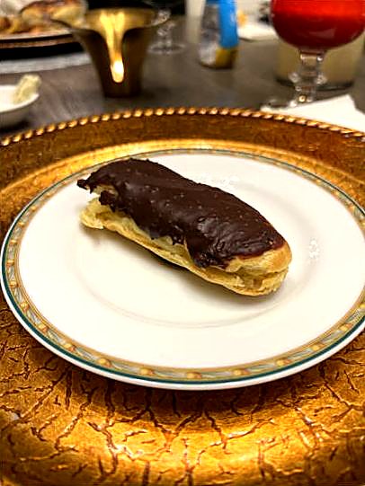 A chocolate eclair on a gold-rimmed plate.